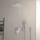 Wandmontierte Dusche von Ideal Standard mit einer großen runden Kopfbrause und einer Handbrause, verchromte Armatur, einfache Bedienung. Helle Längswand im Hintergrund.